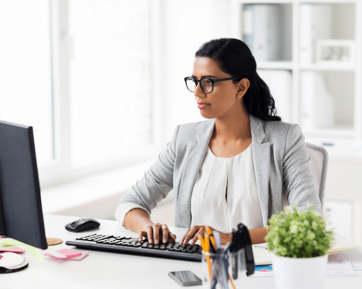 woman working at computer to Synchronize Master Data between her core logistics systems and key third-party applications.