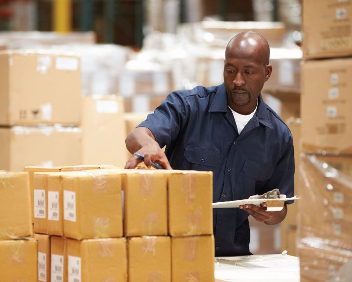 Warehouse worker quality checking product in boxes.